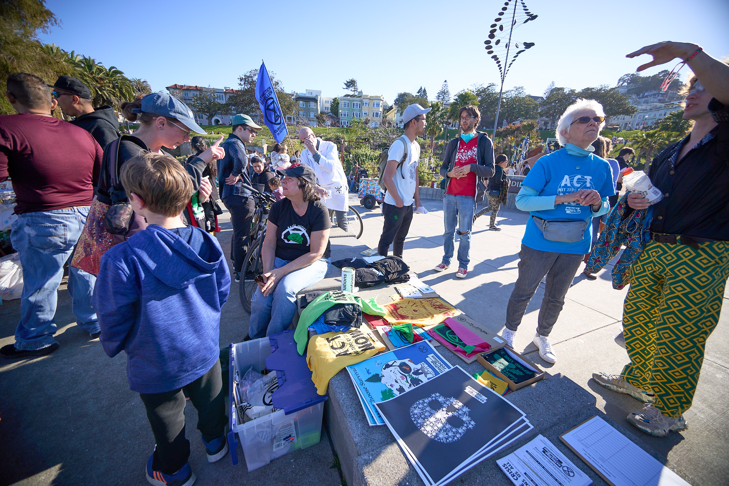 Extinction Rebellion and community members stand talking around a table covered with flyers.